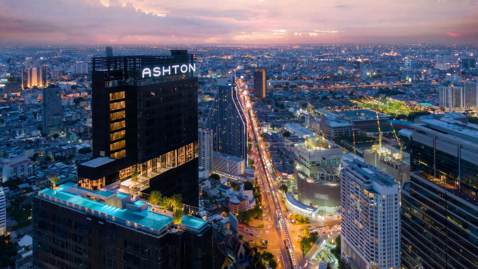 Ashton luxury high-rise with rooftop pools overlooking Bangkok's illuminated cityscape