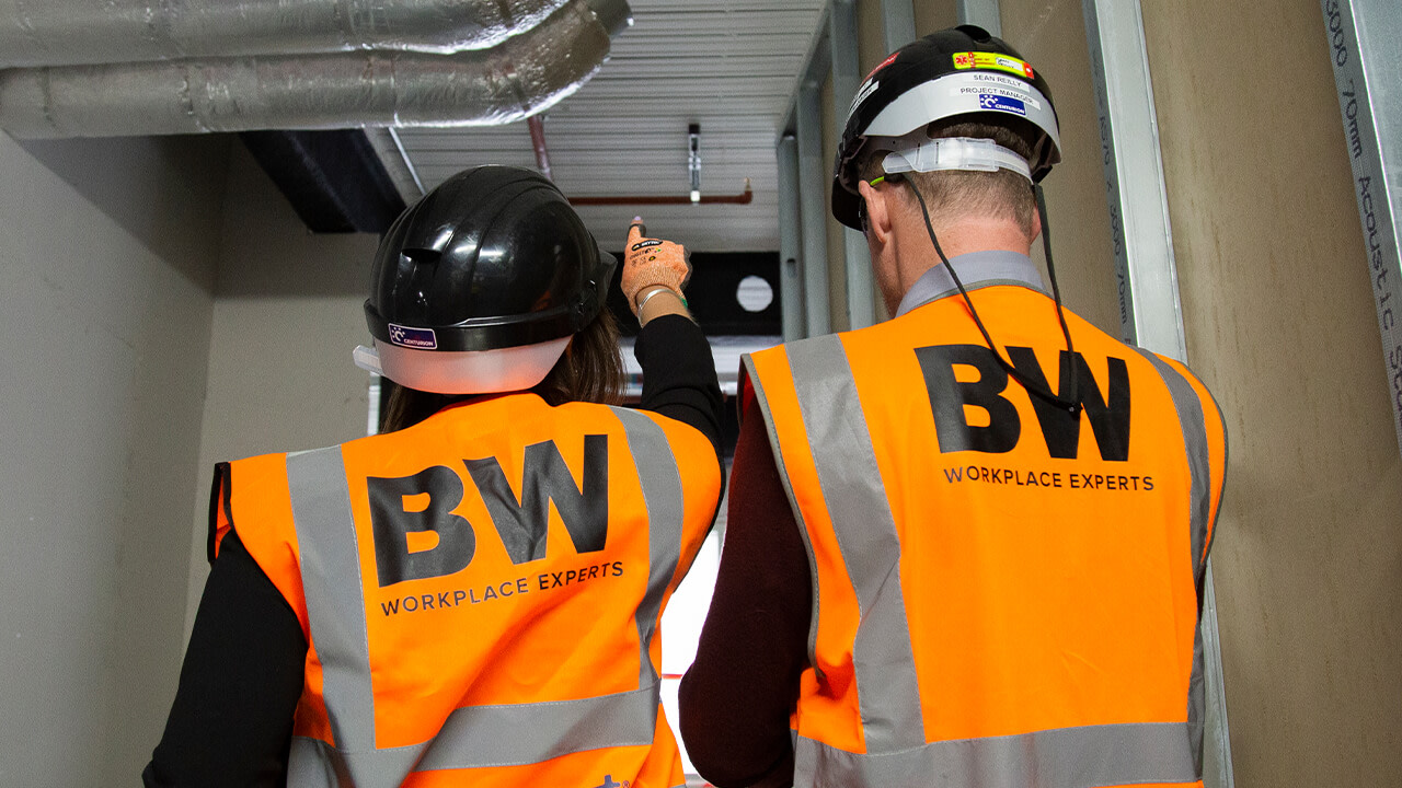 Construction workers in orange TBW safety vests inspect building interior