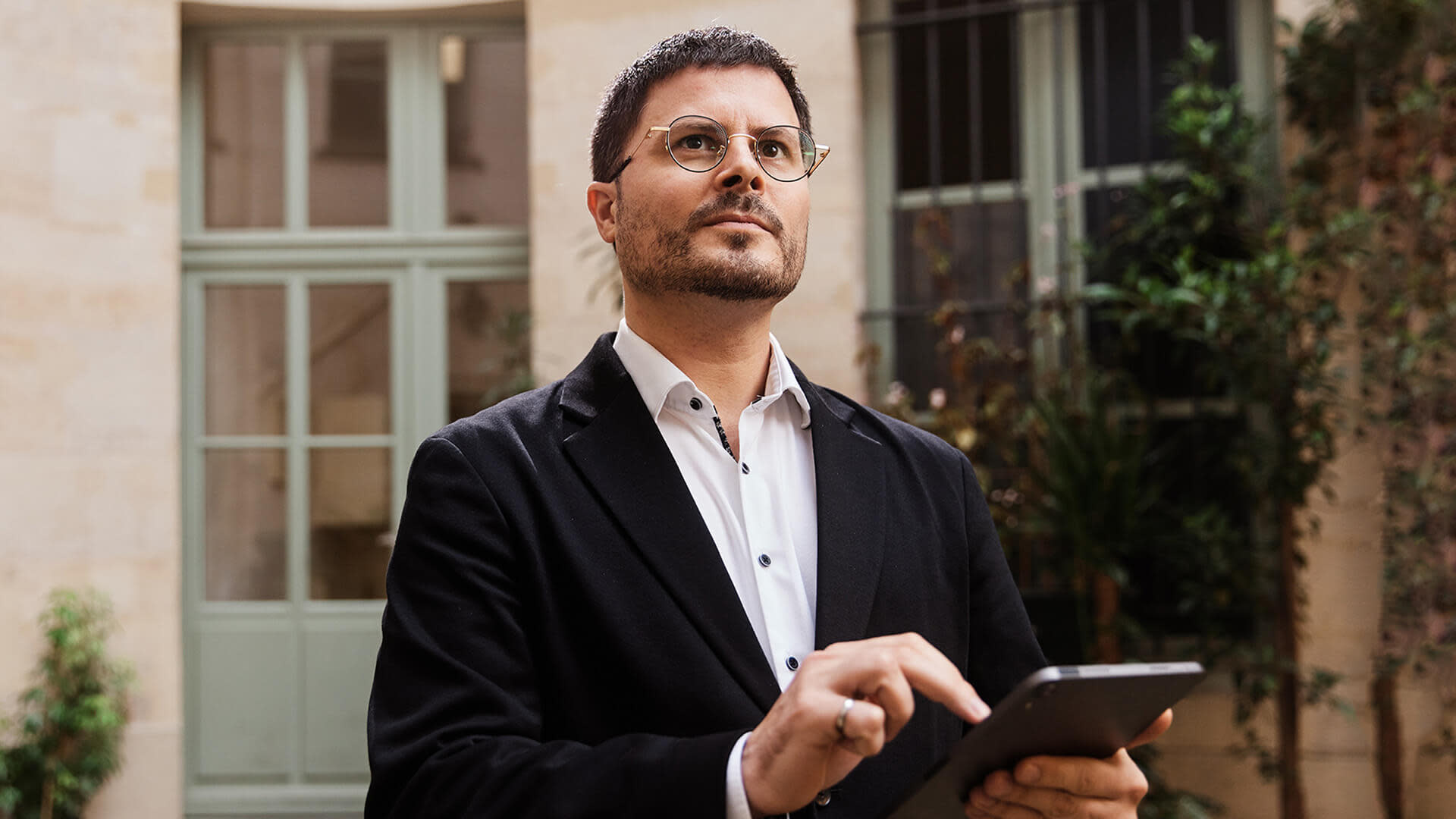 Woman in polka dot shirt using tablet with earphones at office desk