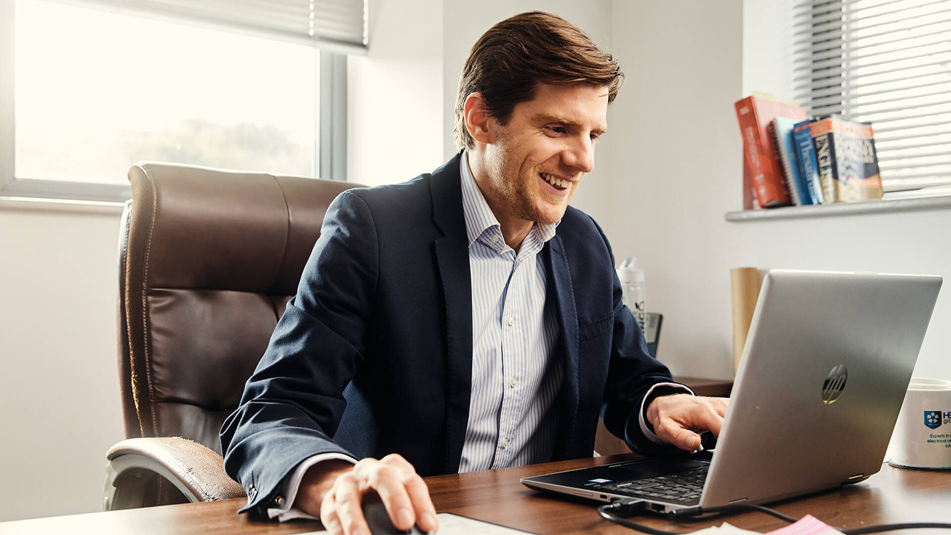 Woman in polka dot shirt using tablet with earphones at office desk
