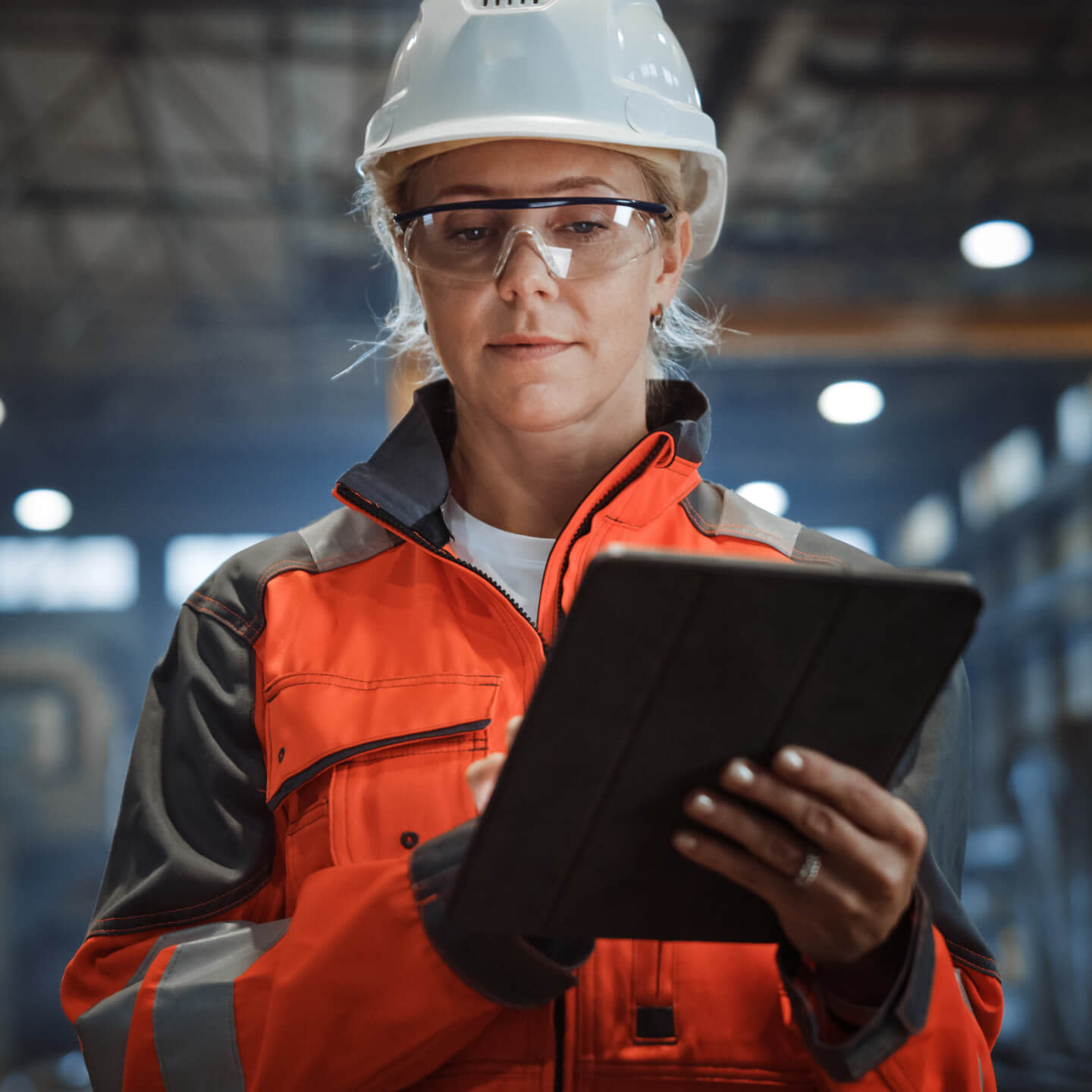 construction worker wearing her safety gear, using Procore in a tablet