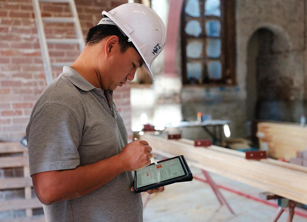 Contractor using Procore on a tablet