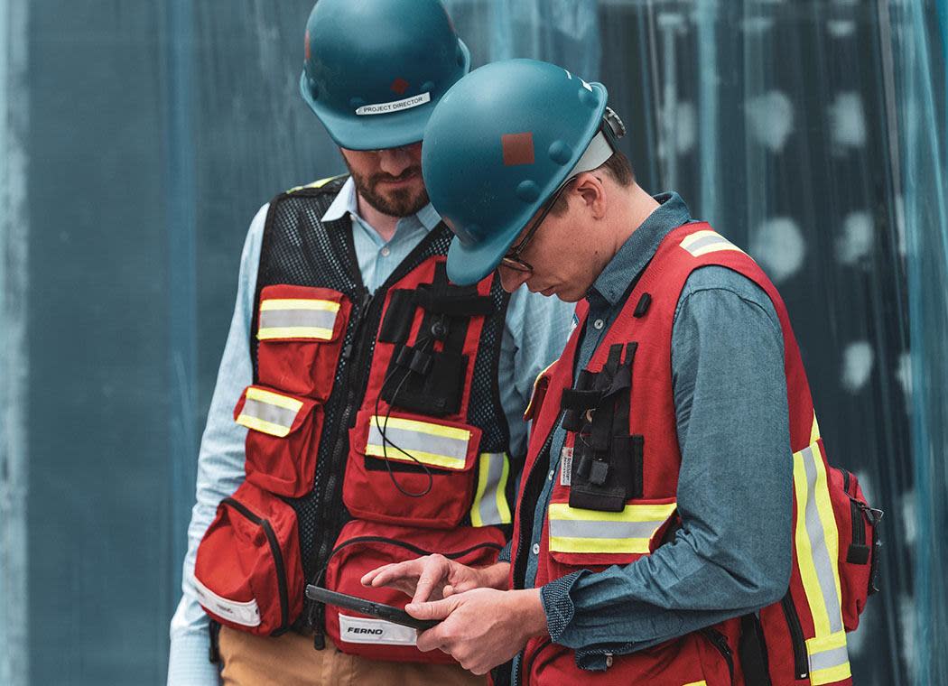 Construction worker colleagues looking at Procore software together on a device