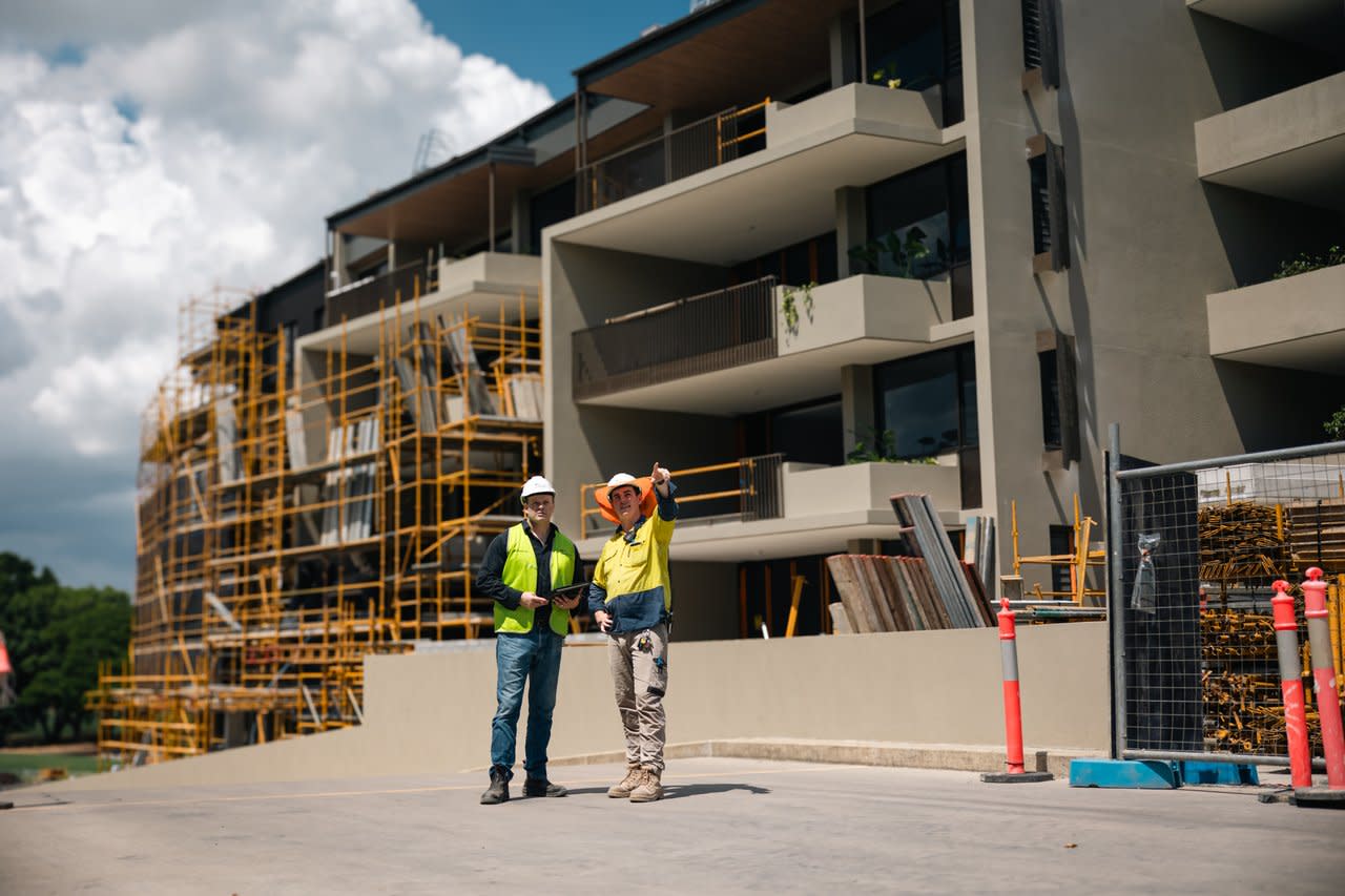 Two contractors using a tablet while pointing at a construction site