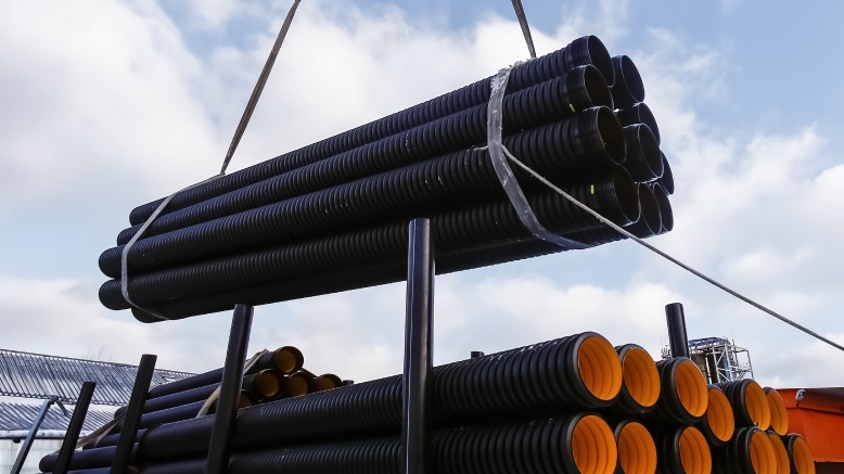 Corrugated pipe being crane-loaded onto a transport vehicle