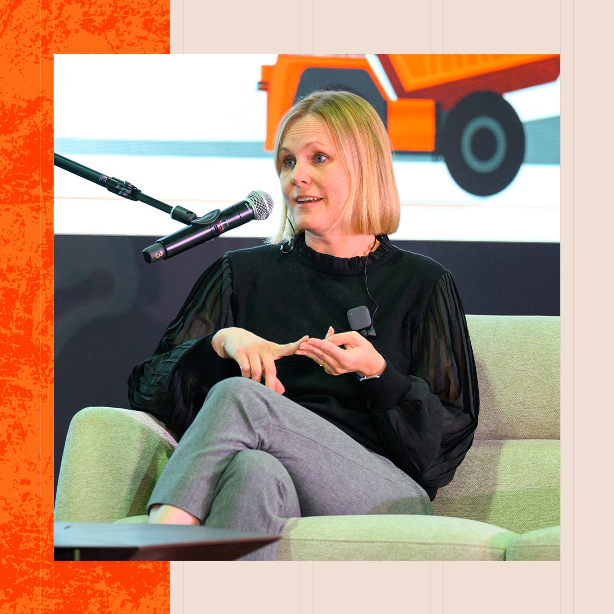 A woman sitting on a couch, speaking through a microphone