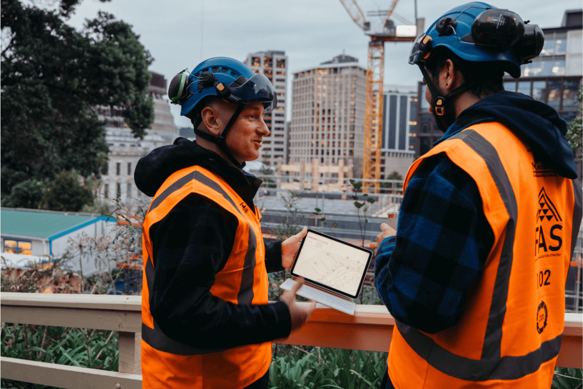 Construction workers on site reviewing plans on tablet