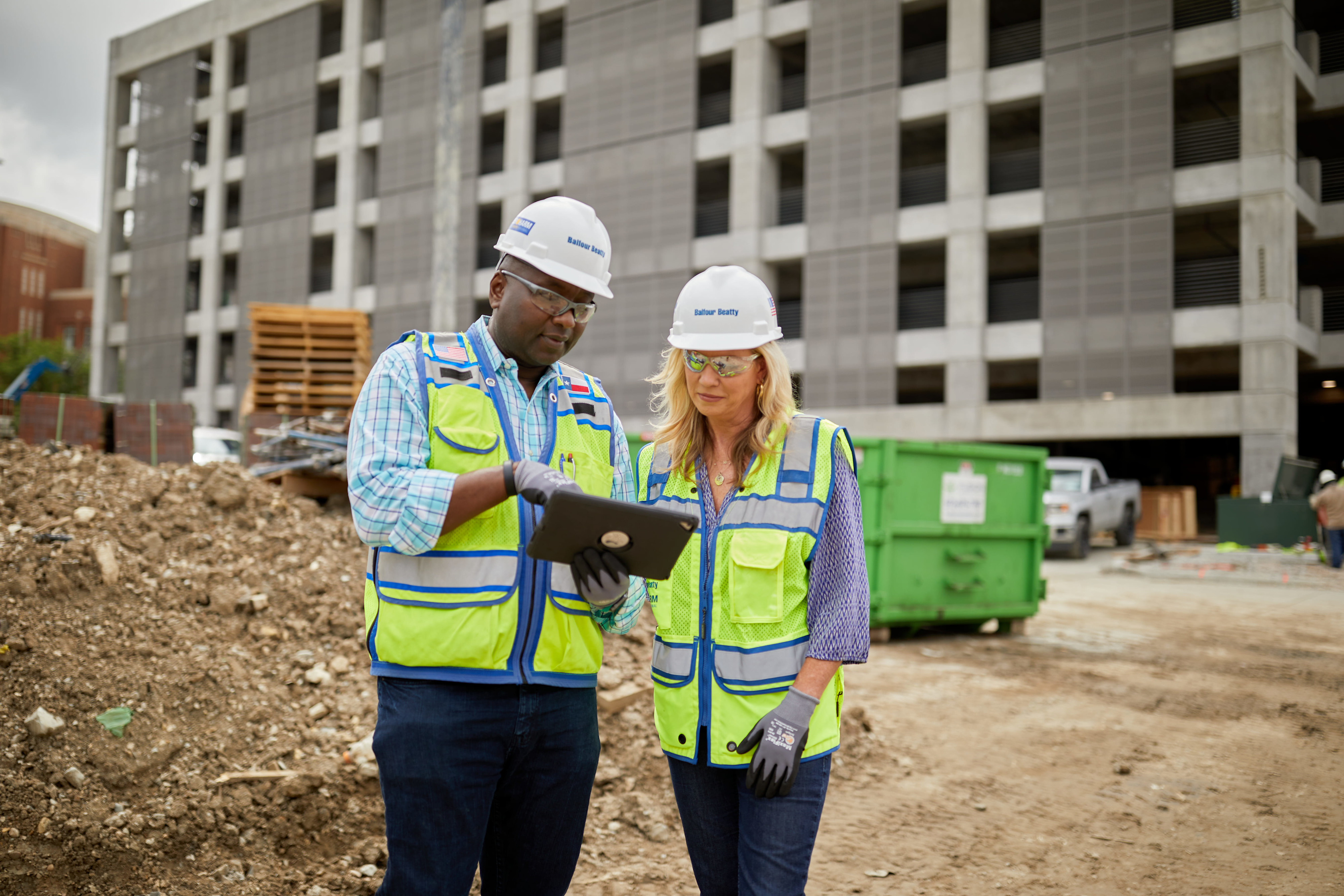 Two construction workers using a tablet at a construction site