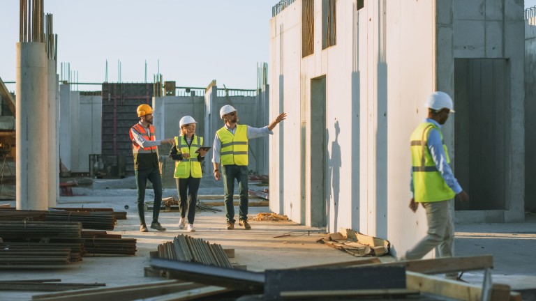 A group of people in safety vests and helmets walking on a construction site