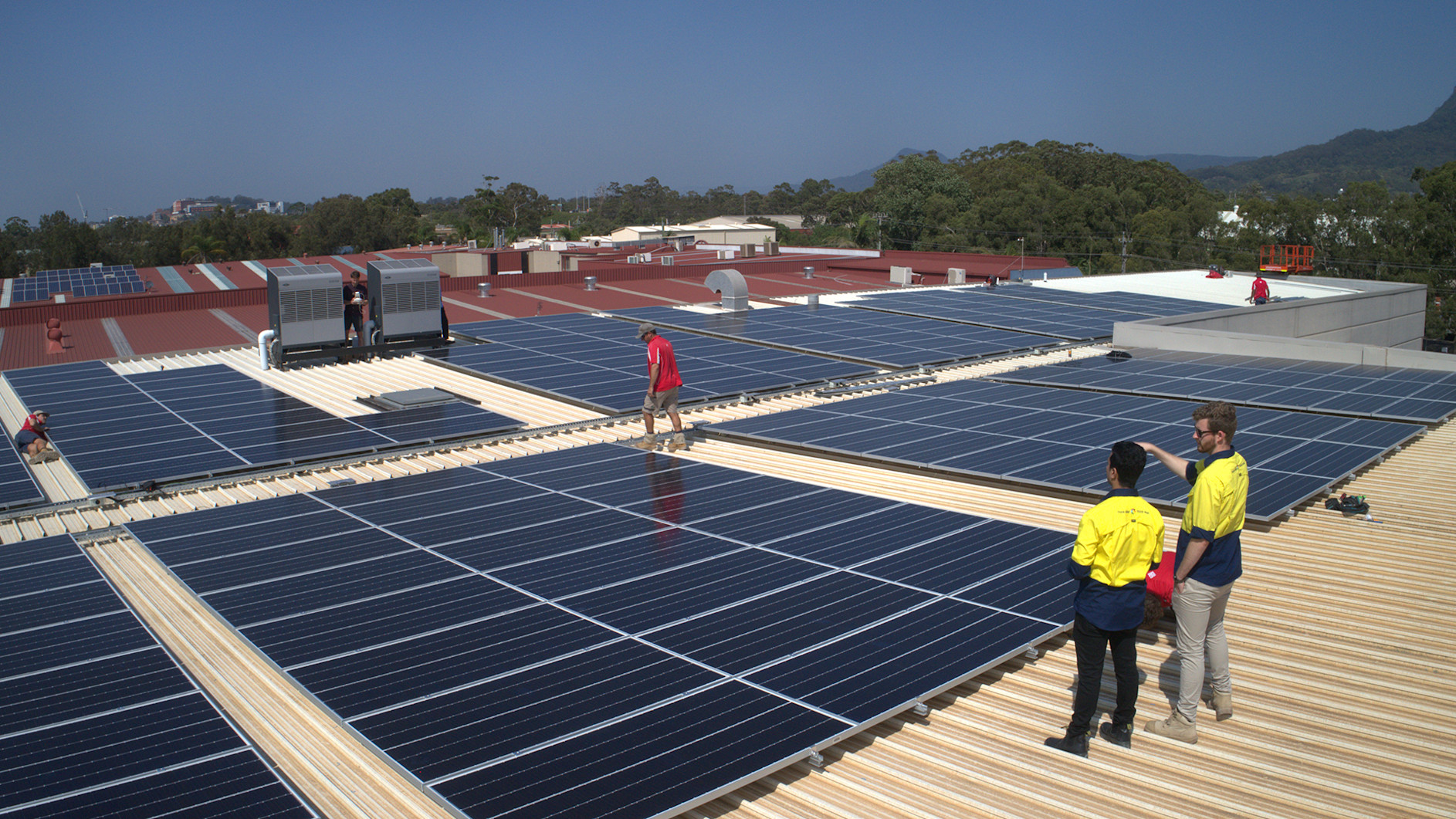 Image of construction workers on a roof inspecting solar panels