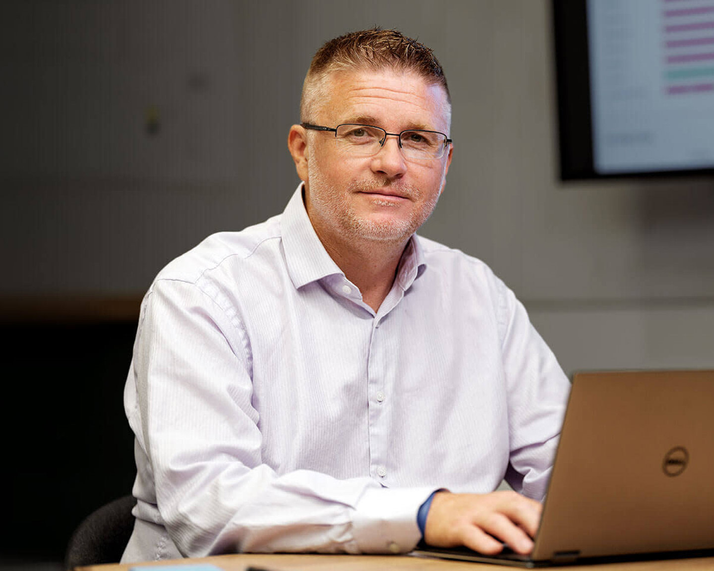 Person sitting behind a computer looking into camera