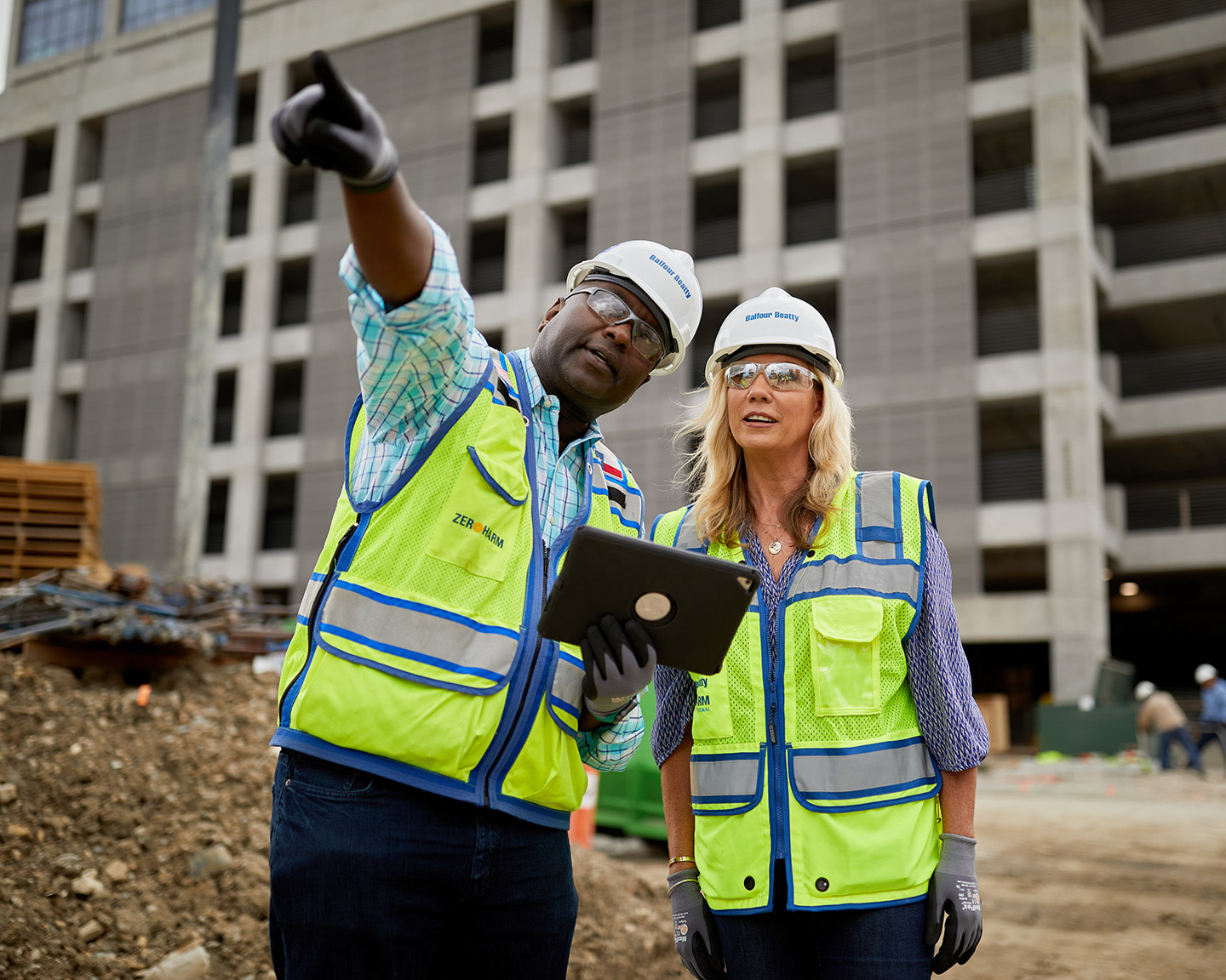 Construction worker pointing at the site while speaking to another worker, with large negative space on the left