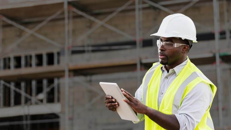 A worker using Procore on an iPad at a construction jobsite