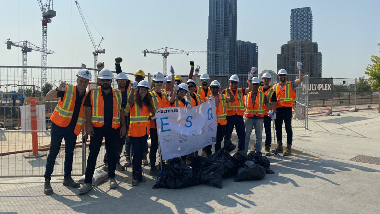 Multiplex workers standing in front of a construction site holding a sign