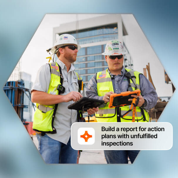 Two construction workers in hard hats and yellow vests consulting tablets at a job site
