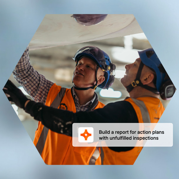 Two construction workers in hard hats and yellow vests consulting tablets at a job site