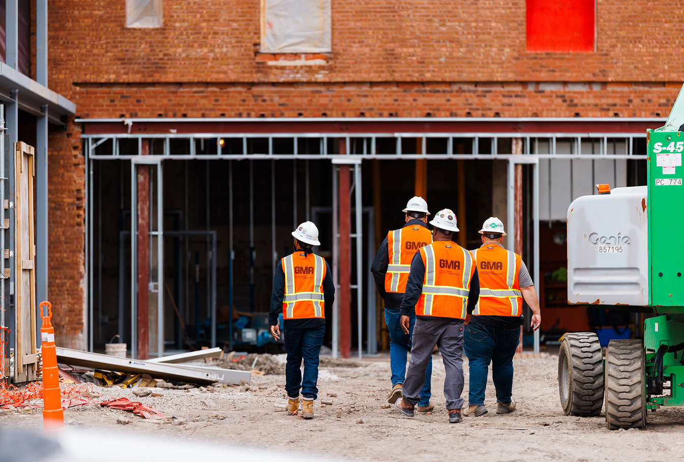 4 construction workers walking towards a building