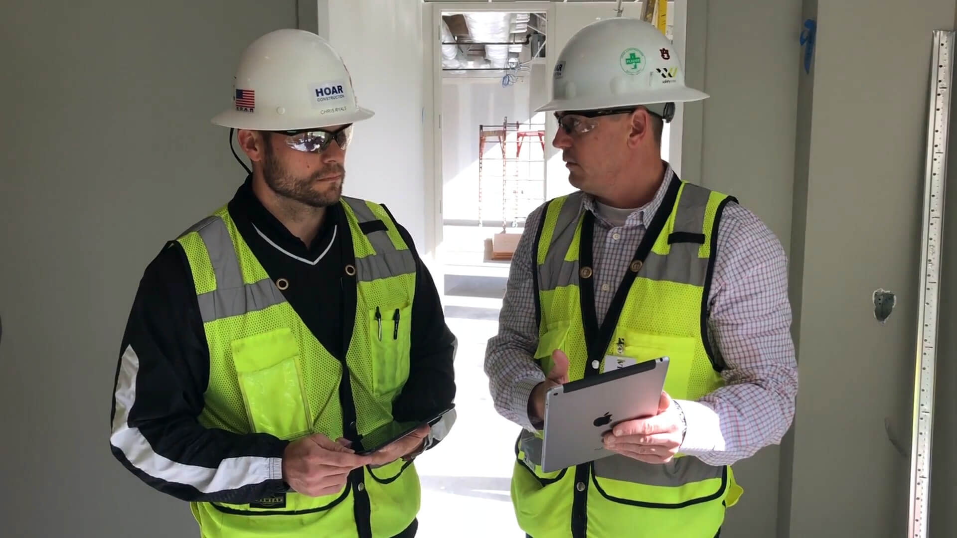 Contractors collaborating over Procore on a tablet