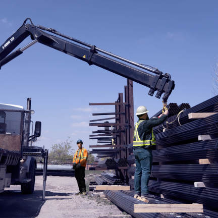 Two construction workers piling up beams