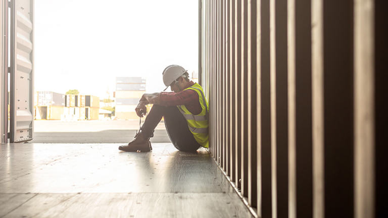 A construction worker sitting on the floor with his head down