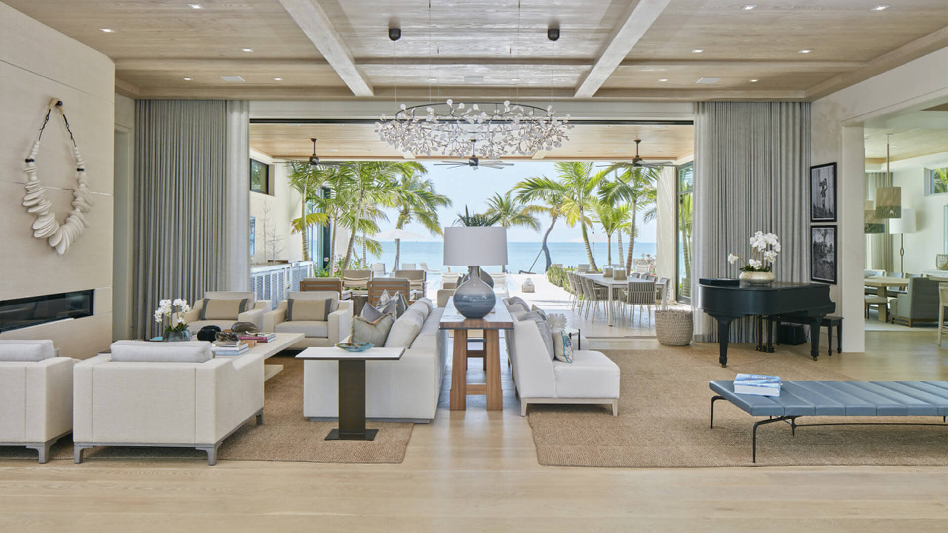 Luxury home's loving room with an open glass door to the backyard leading to the beach