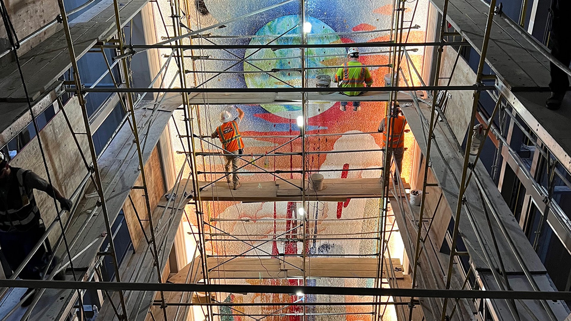 a group of men in safety vests standing on scaffolding