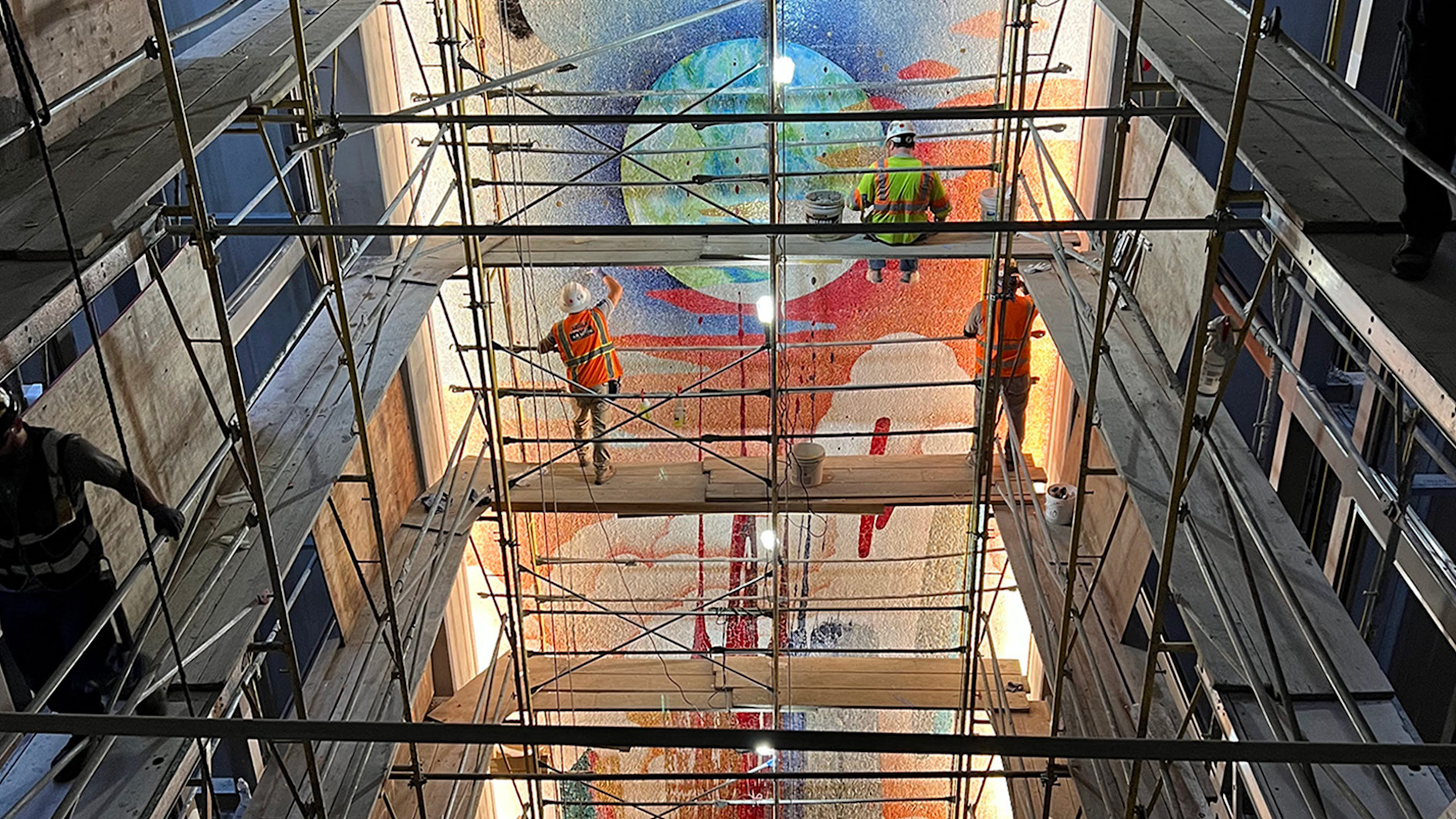 a group of men in safety vests standing on scaffolding