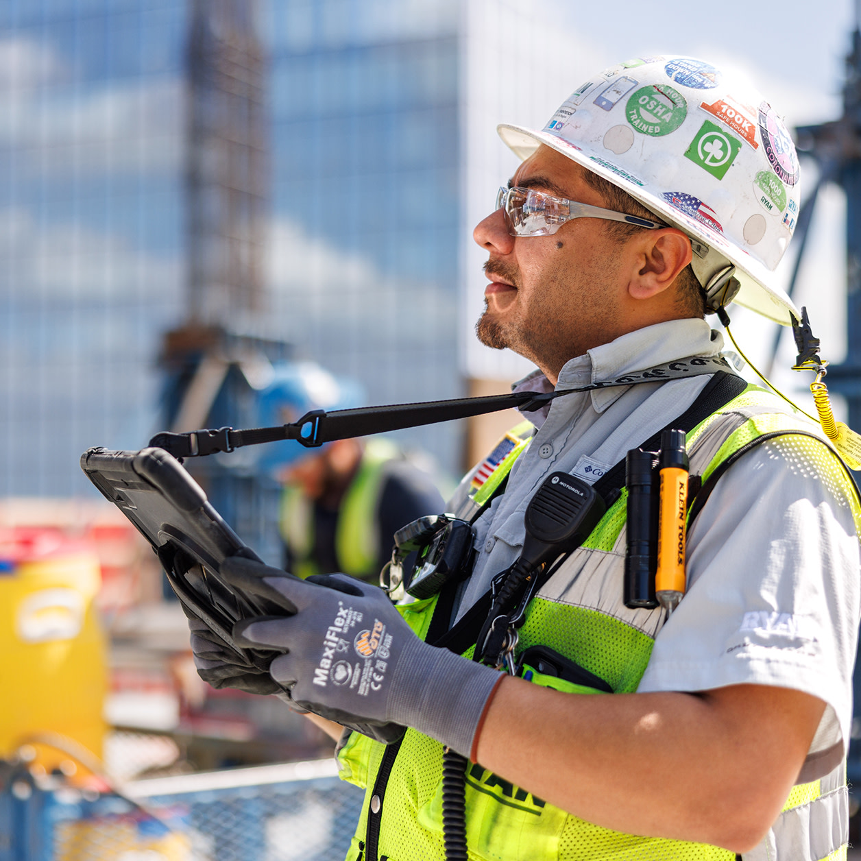 A construction worker carrying a tablet at a construction site