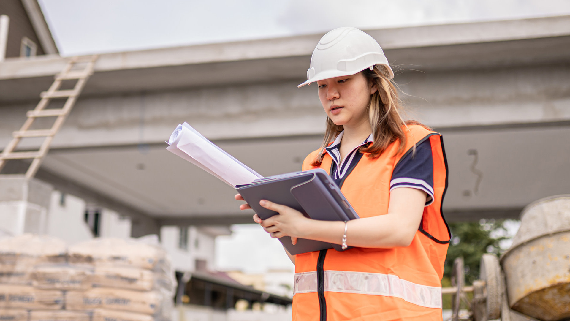 A woman carrying a tablet and blueprints