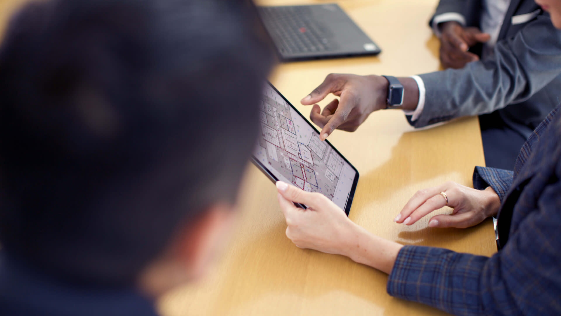 Men in an office using Procore on a tablet