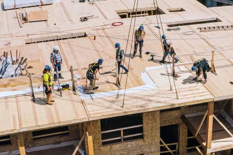 Aerial view of construction workers on top of an unfinished building 