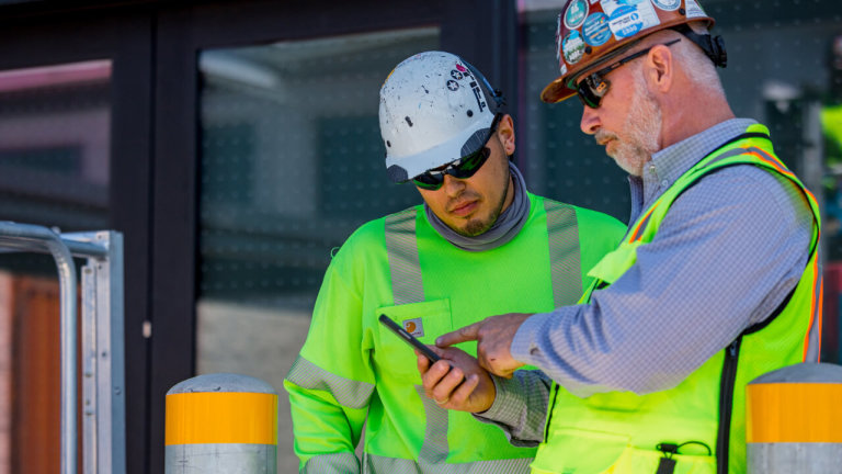 Contractors looking at a project on Procore on a phone