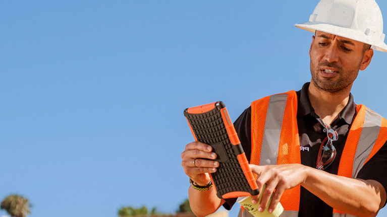 Construction workers using Procore on an iPad on a jobsite