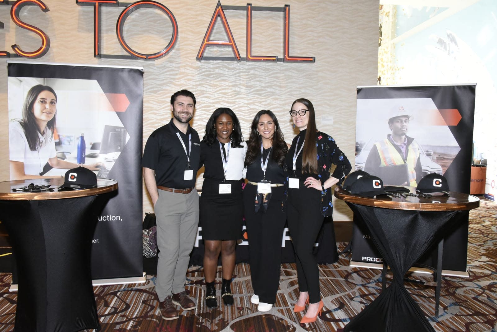 Four professionals smiling at a conference booth with promotional banners.