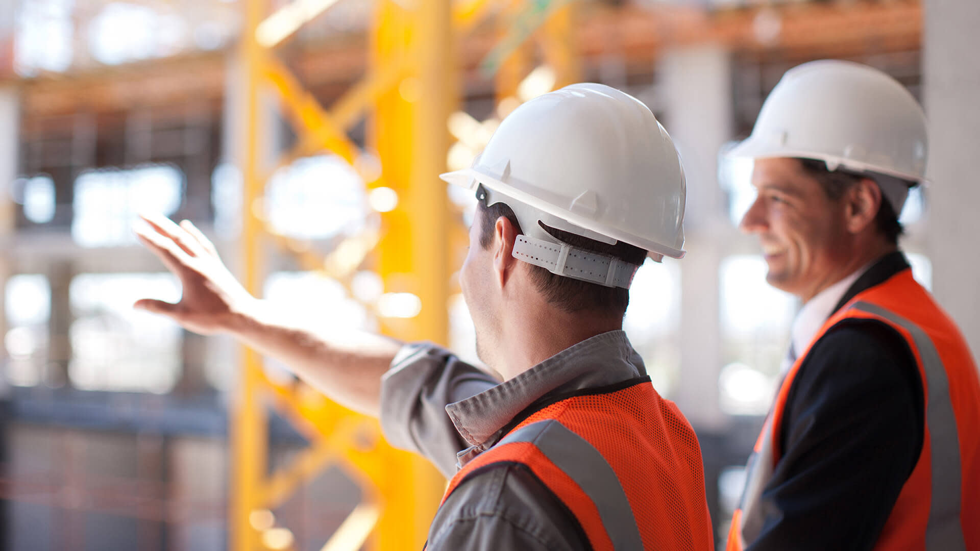 Construction workers having a conversation while looking out at the site