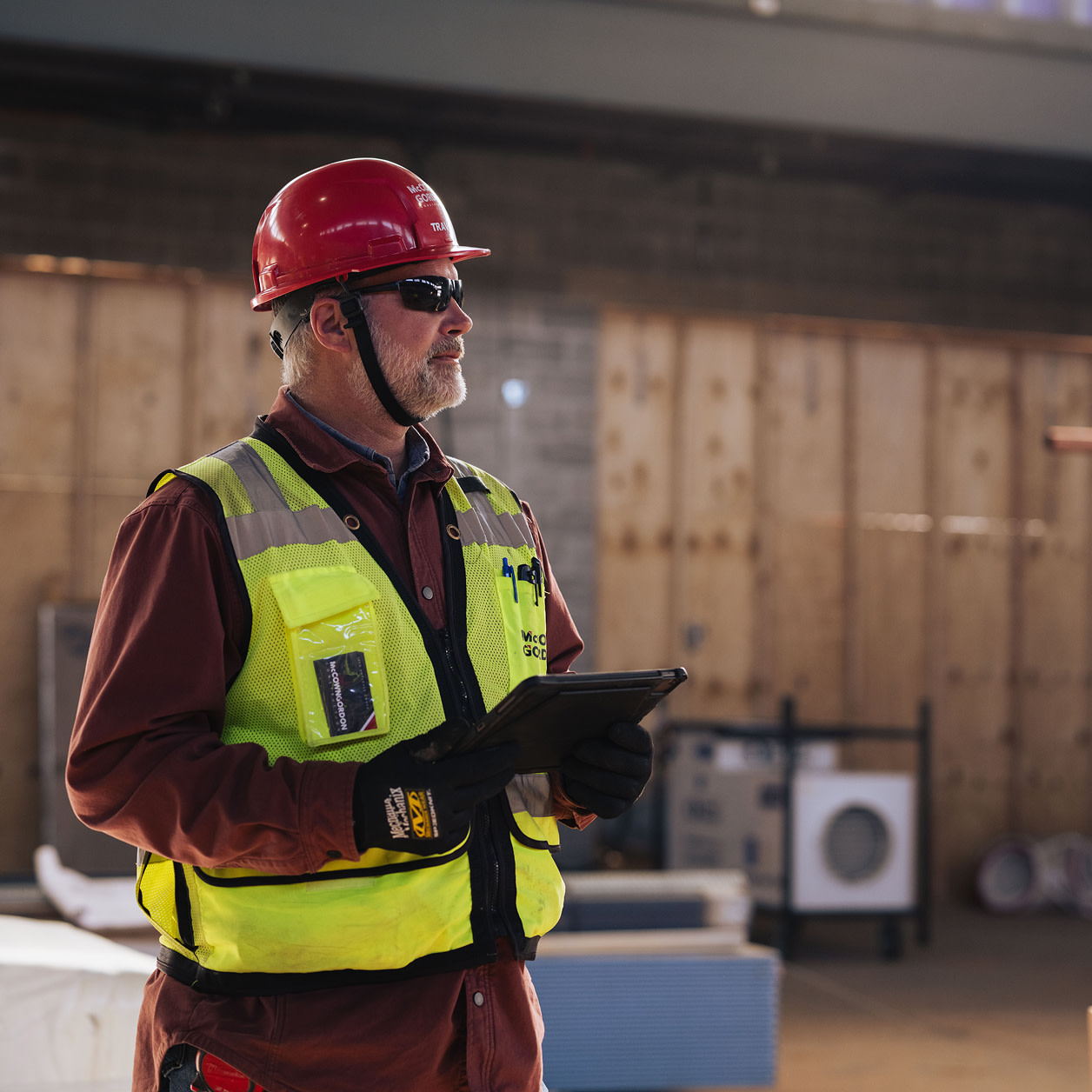 A contractor looking at a construction site while holding a tablet