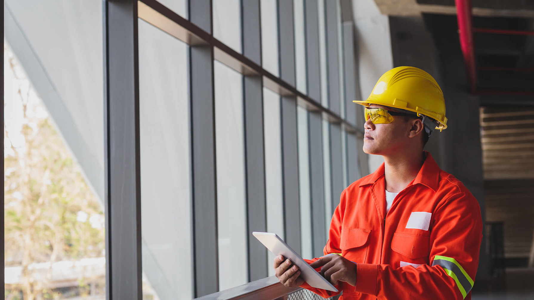 Contractor looking out the window while holding a tablet