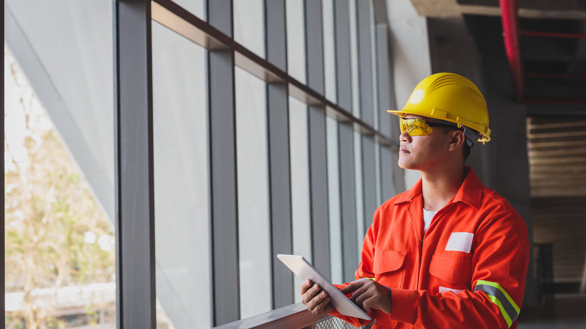Contractor looking out the window while holding a tablet