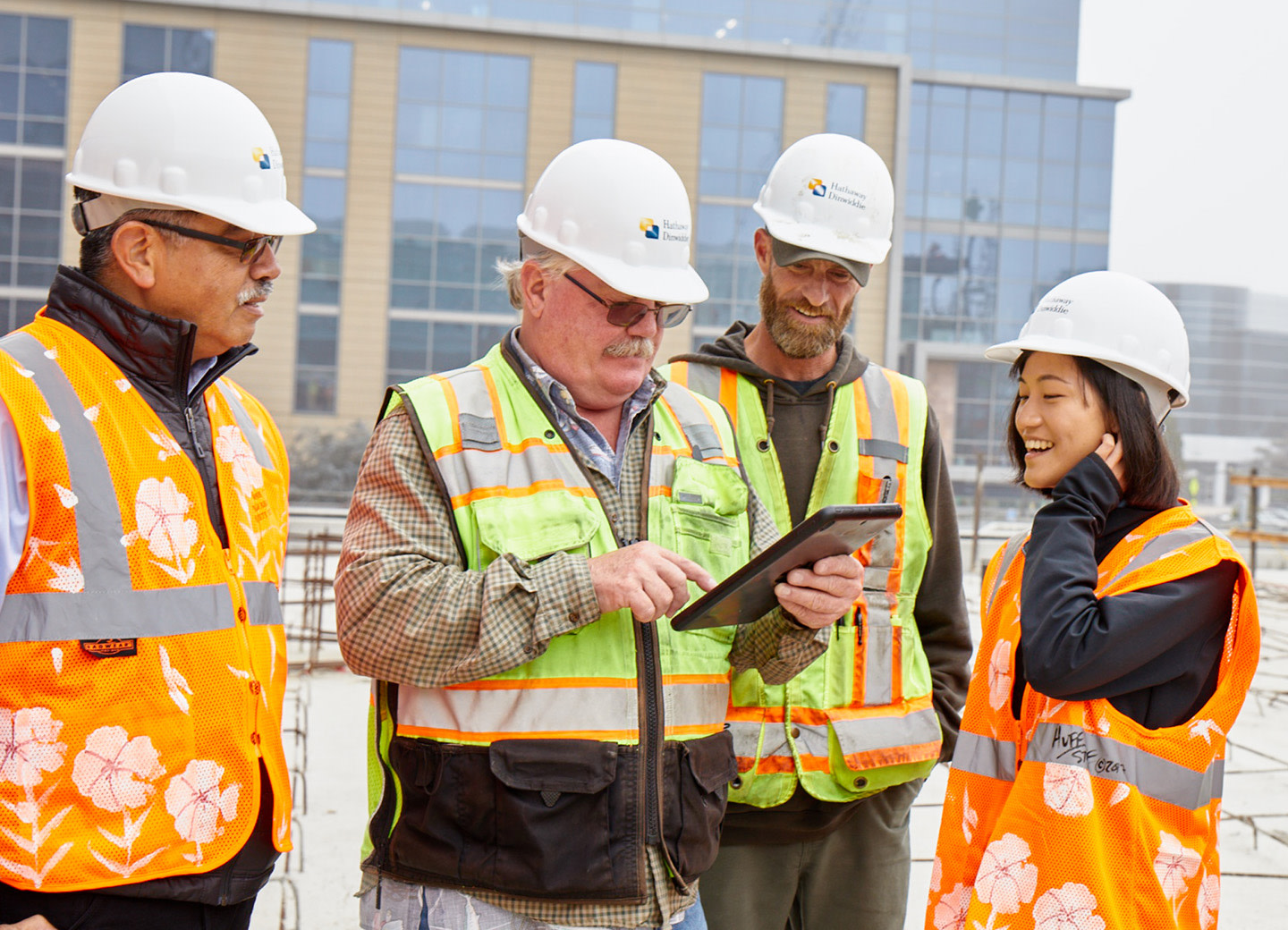 A group of construction workers in orange vests and white hard hats