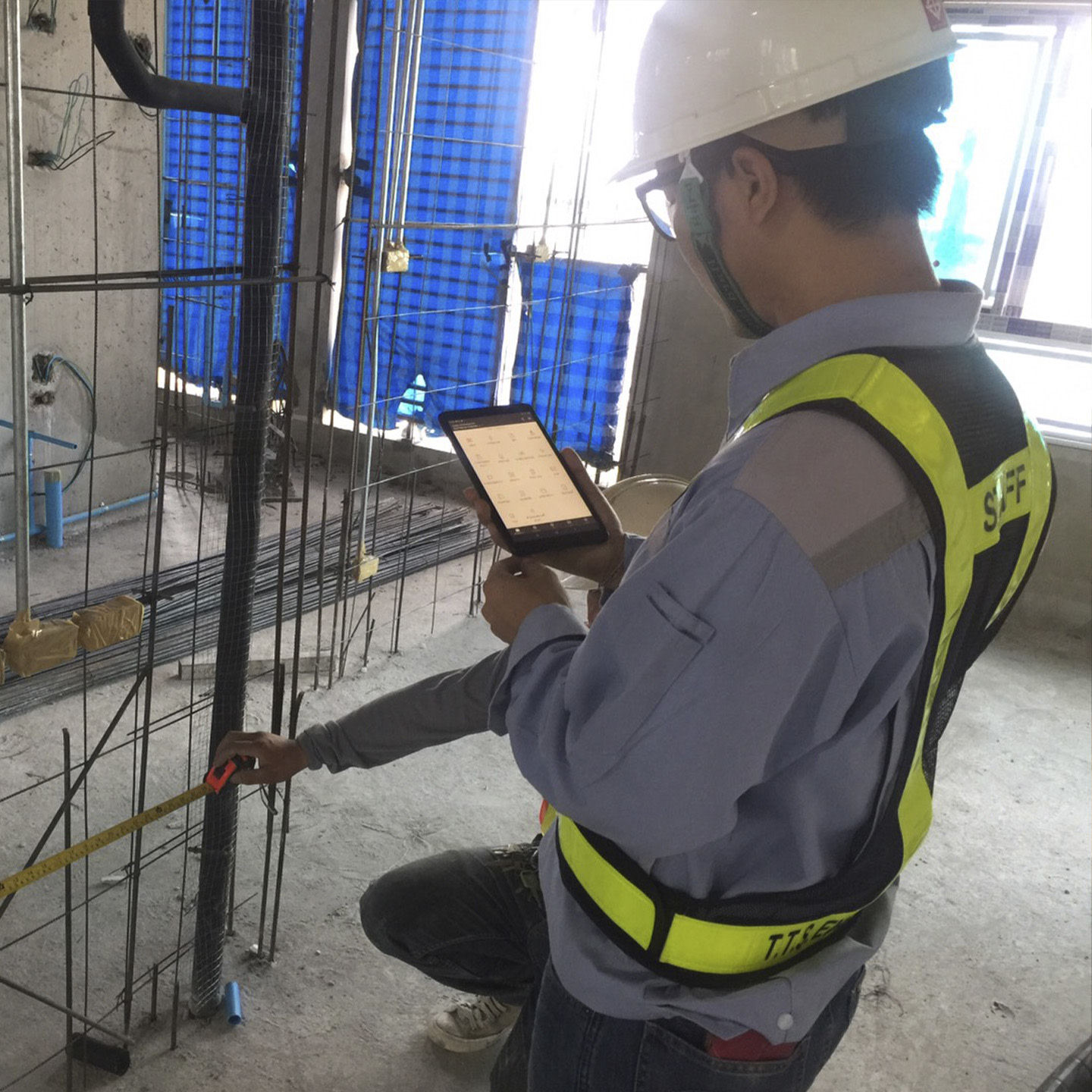 Contractor using an ipad while another contractor is taking measures