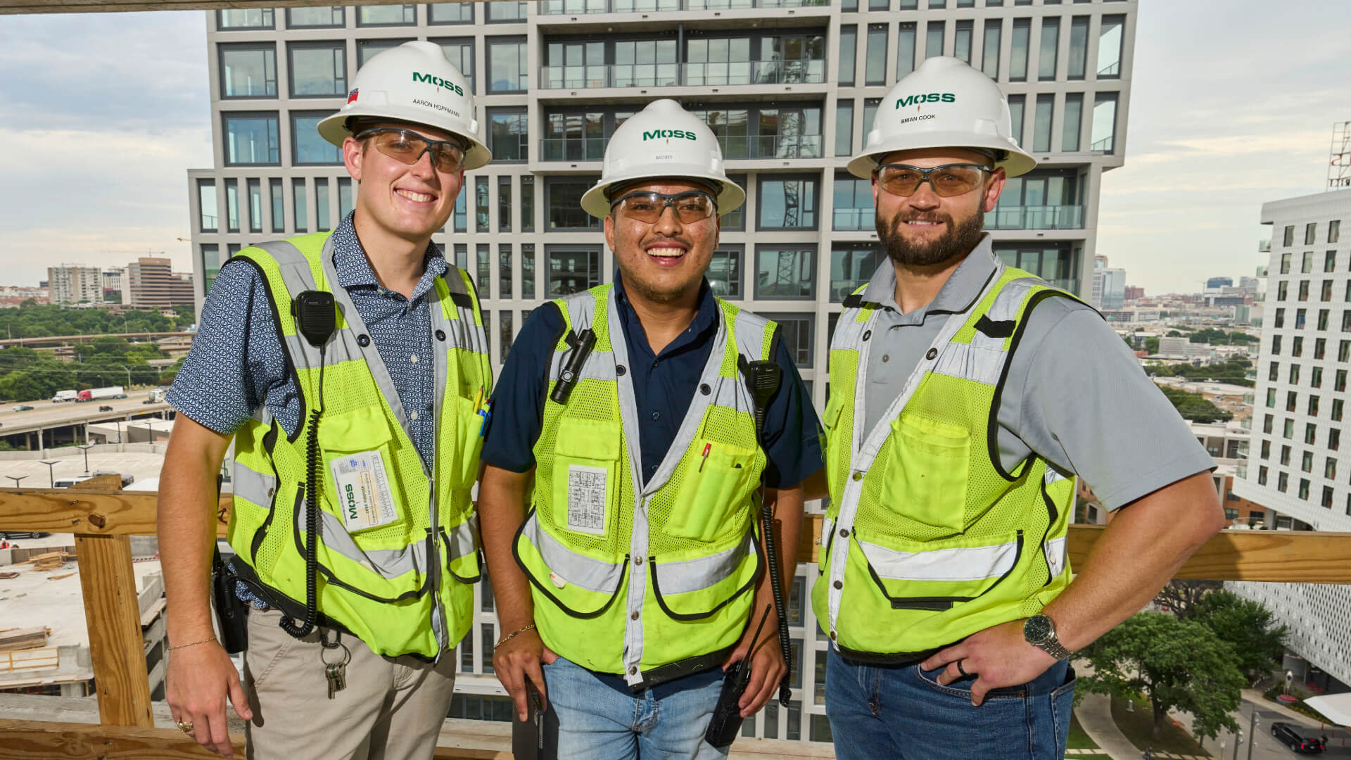 Three Moss workers wearing safety vests smiling for the camera