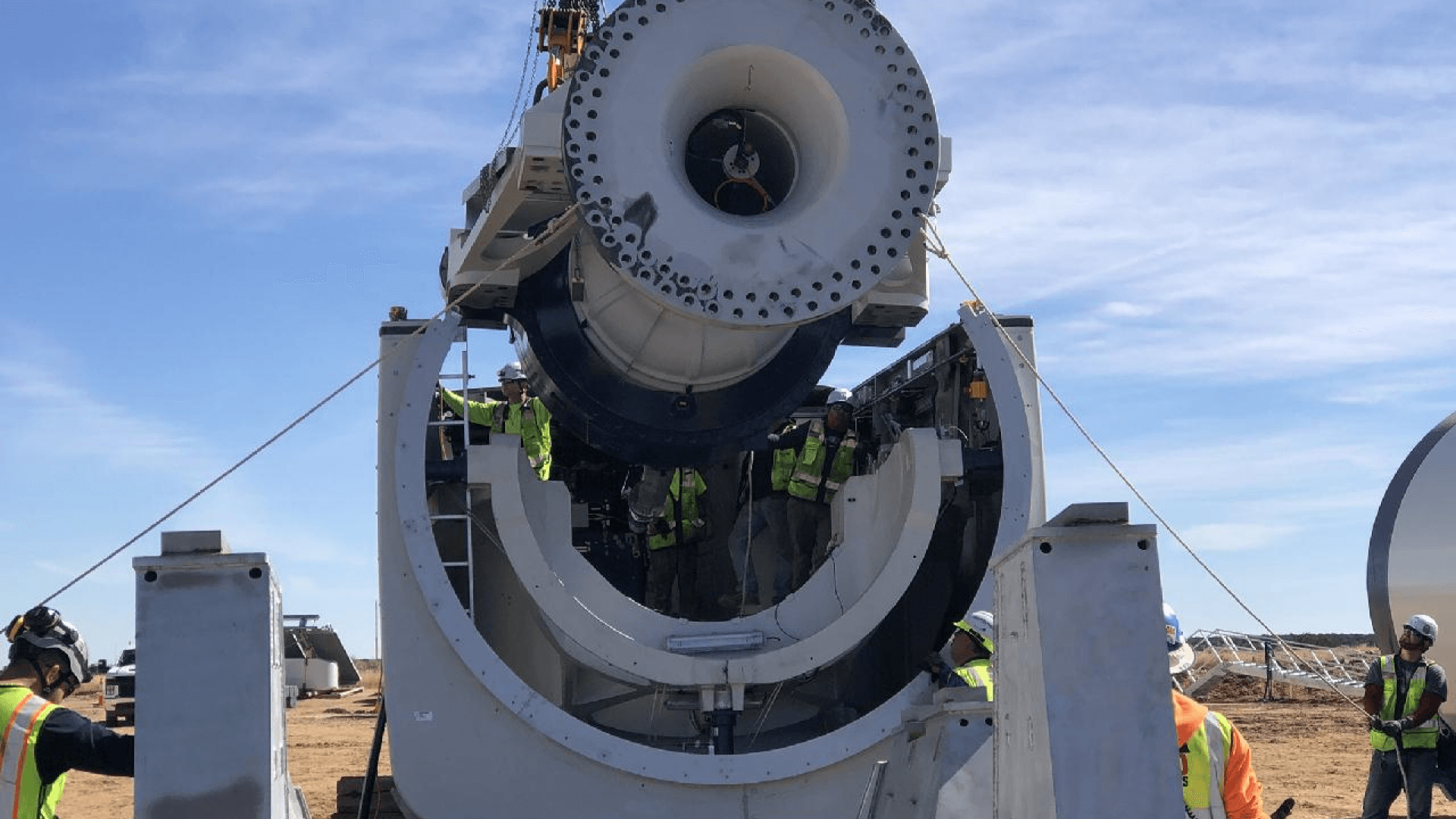 a group of men in yellow vests standing by a large machine