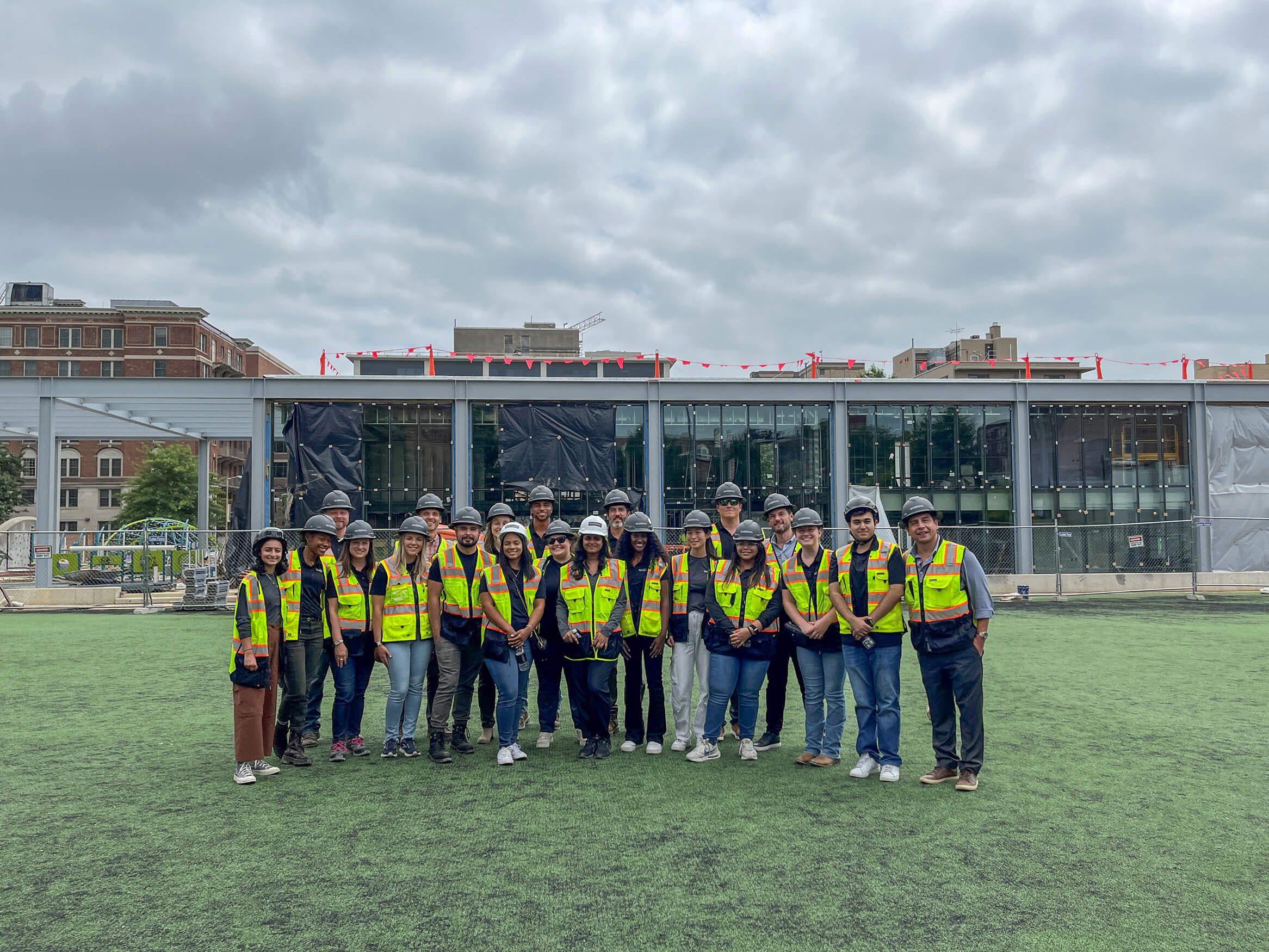 A group GCS-SIGAL workes wearing safety vests standing together on a grass field