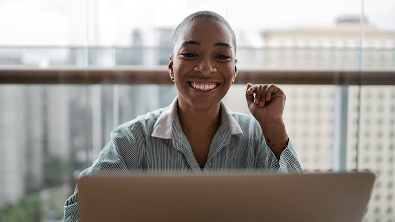 A woman smiling looking at a computer
