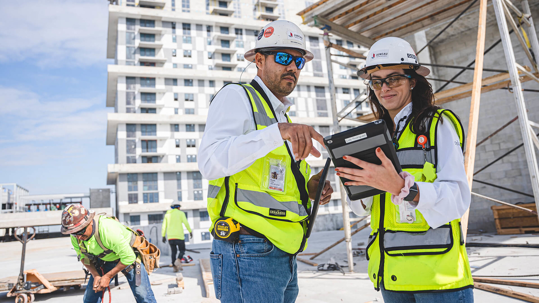 A man and woman wearing safety vests and helmets