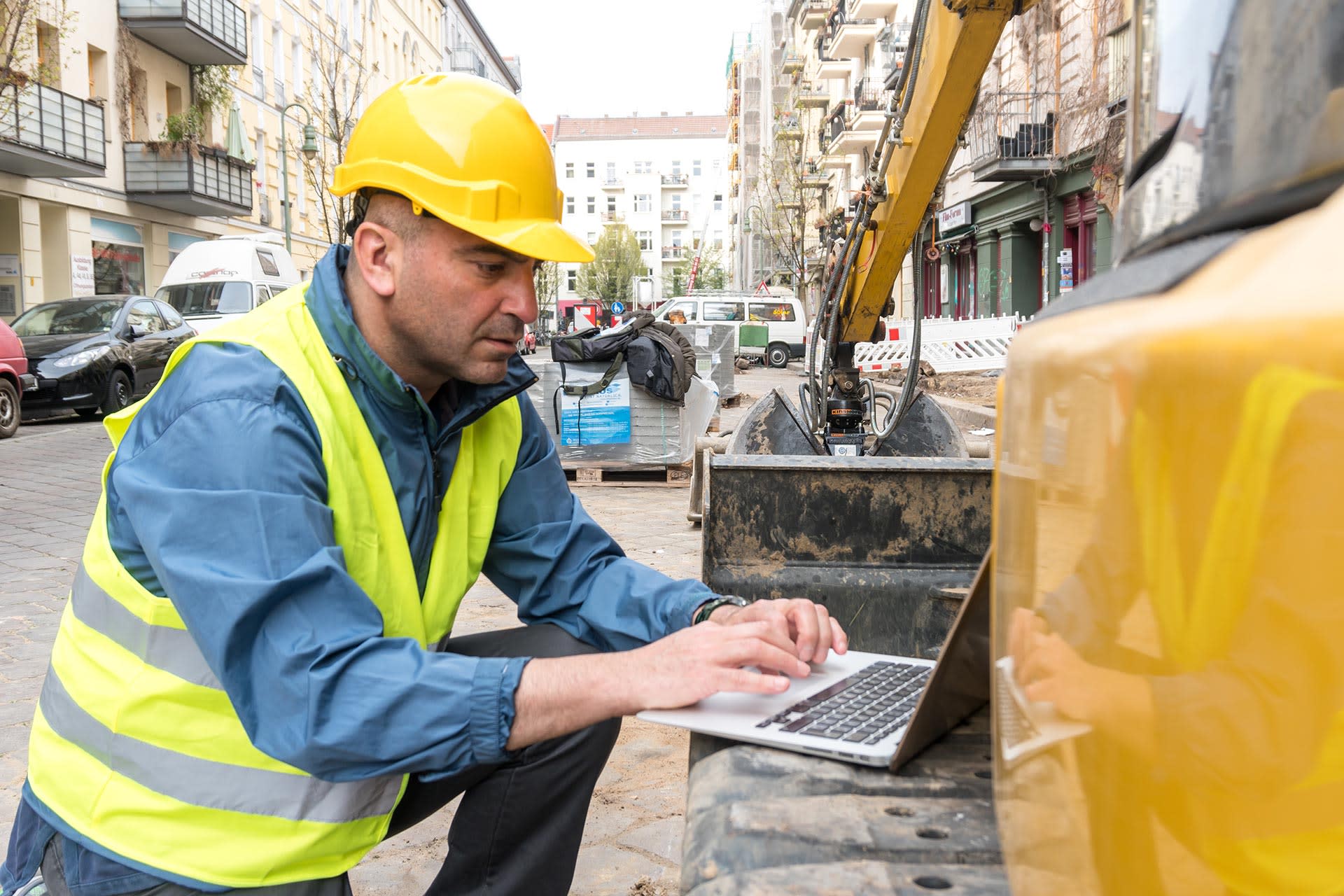 Construction worker on site using Procore on a laptop