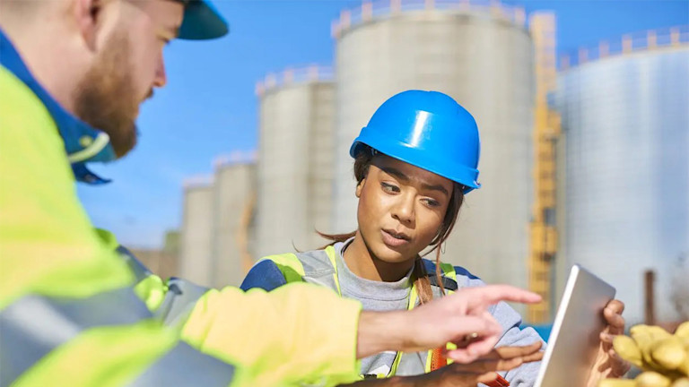 A man and a woman using a laptop on site