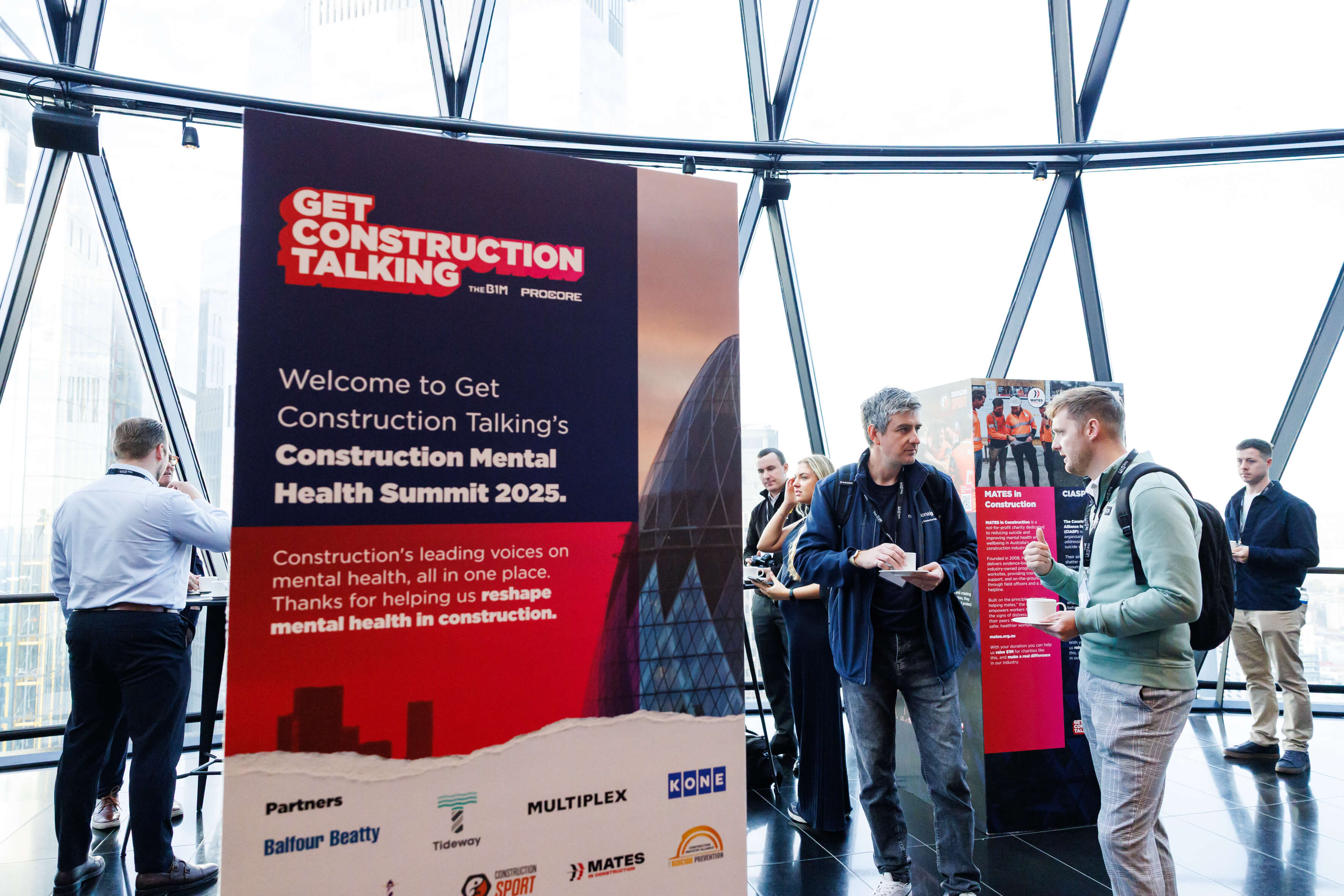 People networking near a sign for Construction Mental Health Summit 2025.
