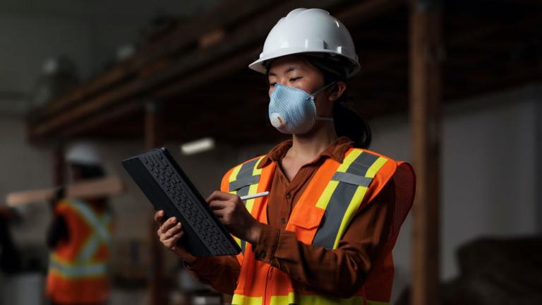 Worker wearing PPE and using a tablet