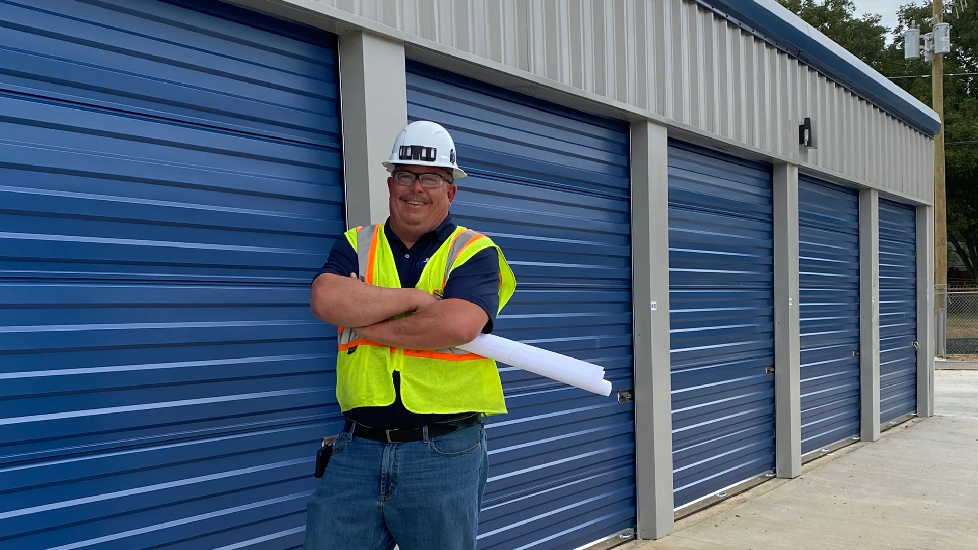 Contractor leaning on a garage while holding a blueprint